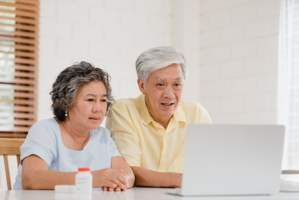 asian elderly couple using laptop conference with doctor about medicine information living room