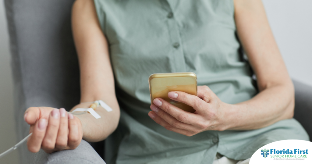 A woman comfortably receives IV therapy at home while using her phone.