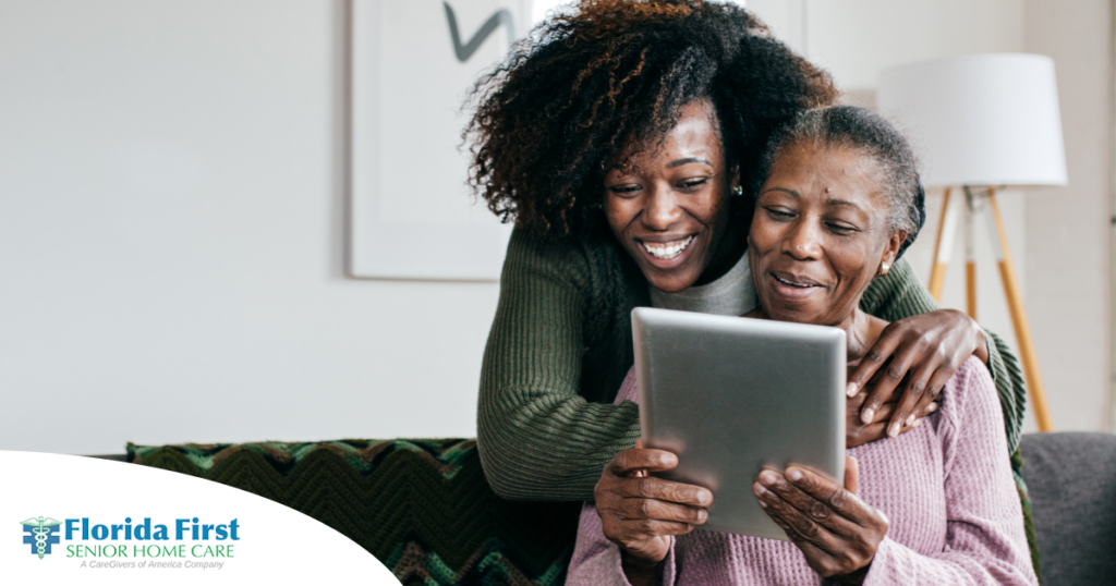A caregiver helps a senior with her tablet, representing the rise of technology in home care.
