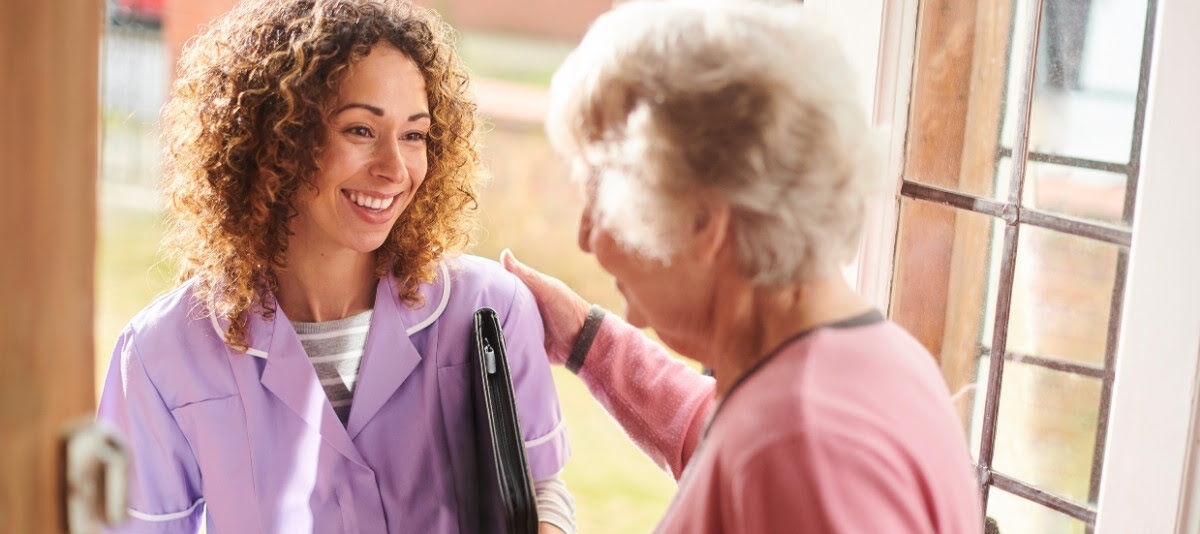 A happy caregiver enters the home of a client, representing in-home recovery care.