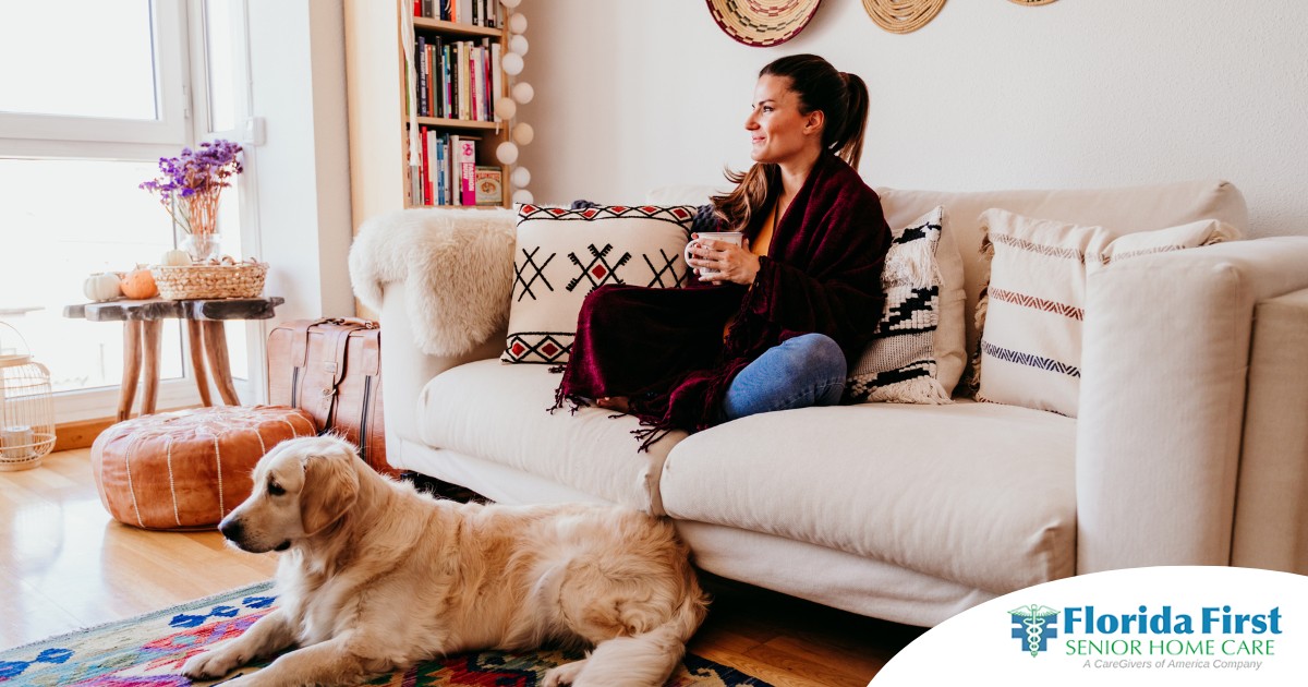 A woman relaxes with her dog while sipping on tea, representing how self-care can combat caregiver stress.