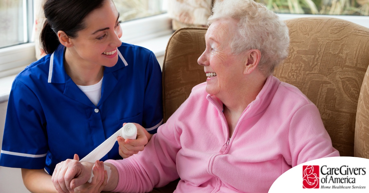 A caregiver demonstrates wound care by wrapping a senior client’s wound.