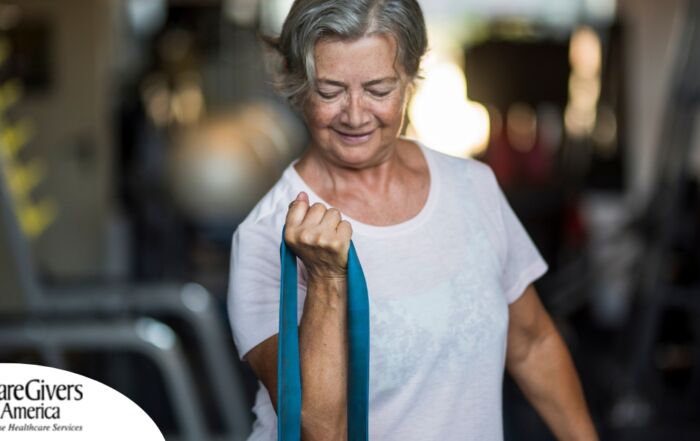 An older woman uses a resistance band to exercise, representing how staying active can help older adults keep their blood pressure in a healthy range.