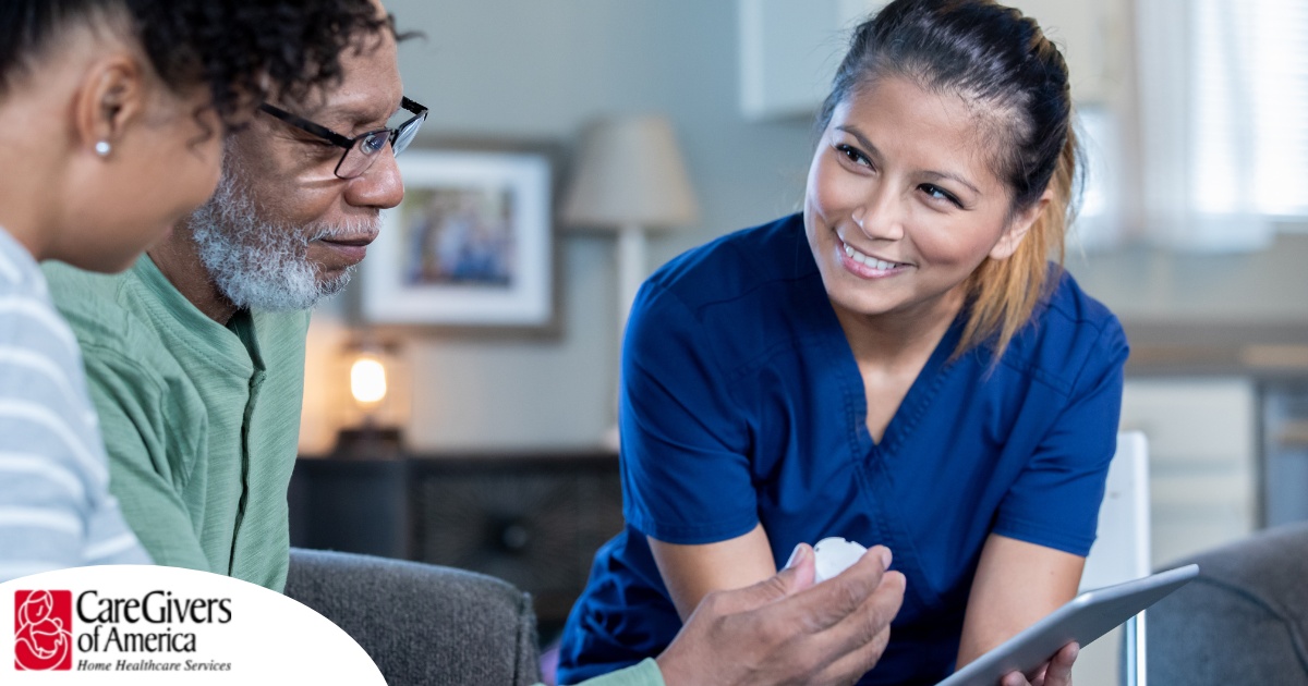 A nurse smiles as she helps an older couple with their medication in the comfort of their own home, showing the benefits of in-home nursing services.