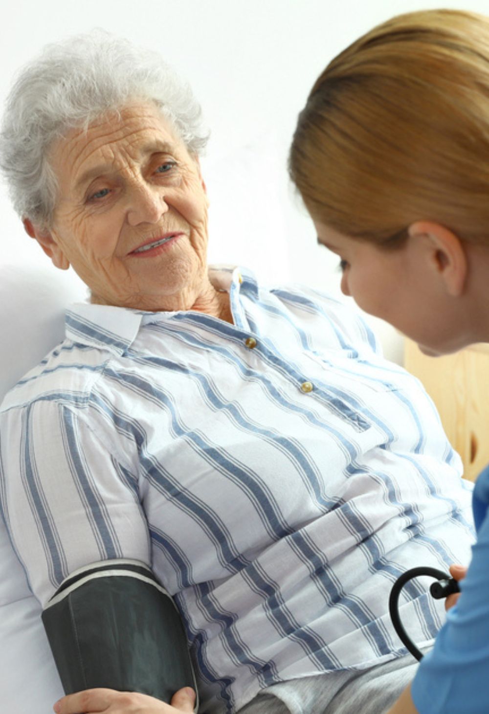 An elderly woman who is having her blood pressure taking by a caregiver.