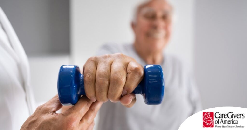 An older man is helped to lift a weight as part of physical therapy.