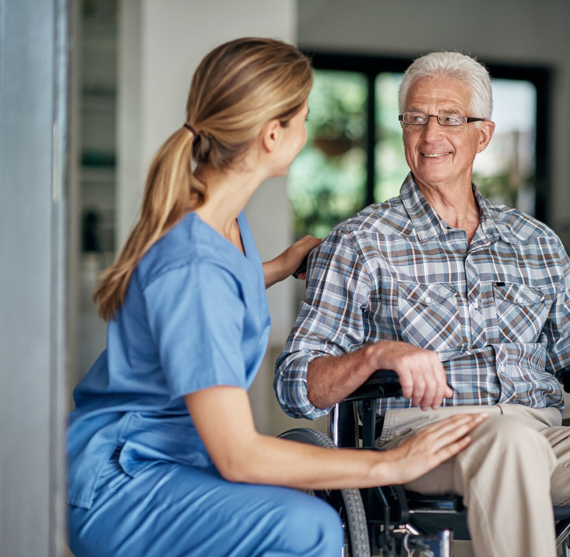 A care giver assists an elderly patient in a wheel chair.