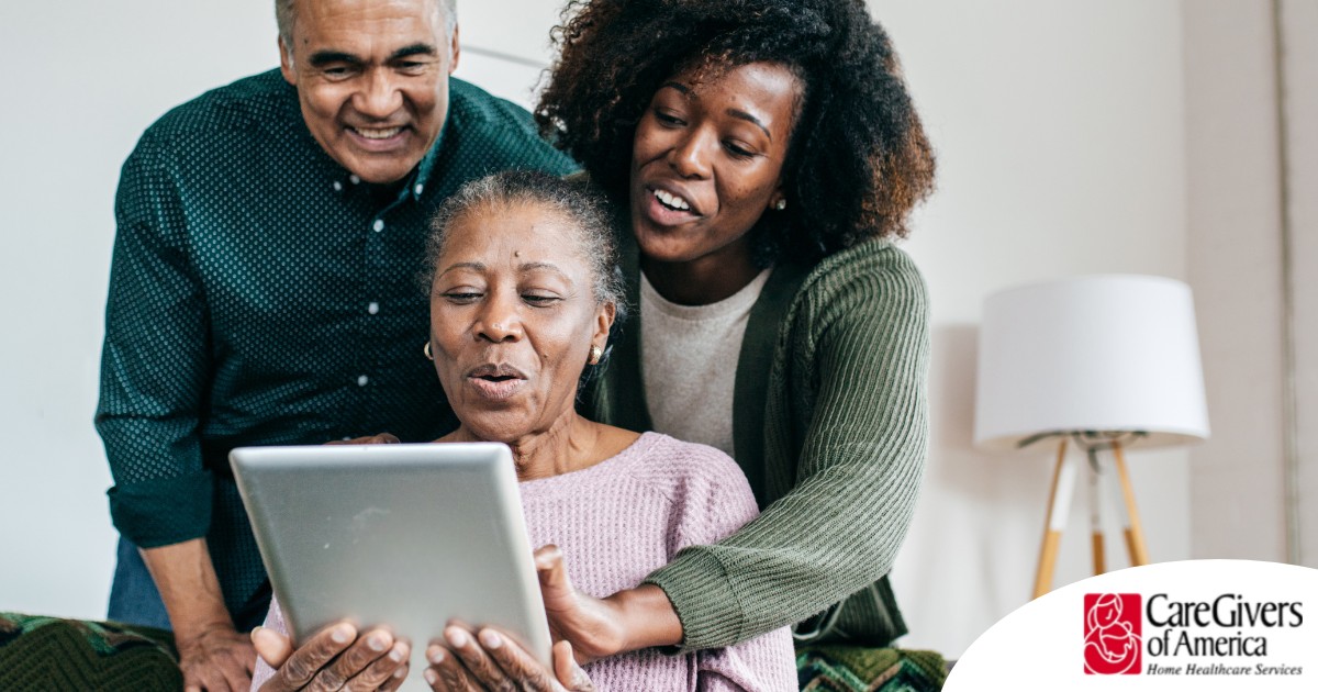 A daughter looks at a tablet with her older parents, representing technology and how ti can help with aging in place.