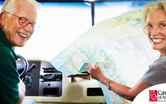 An older couple looks back smiling from the front of an RV, representing how day trips for seniors can help boost the mood of everyone.