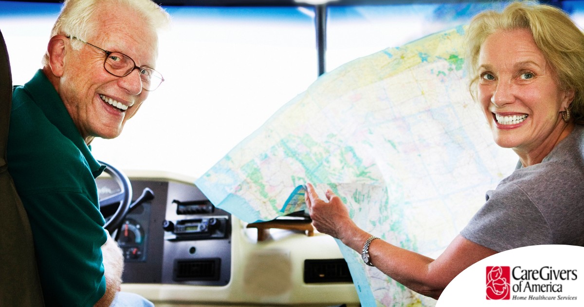 An older couple looks back smiling from the front of an RV, representing how day trips for seniors can help boost the mood of everyone.