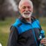 An older man smiles with a water bottle while exercising, representing the benefits of encouraging exercise when caring for seniors at home.