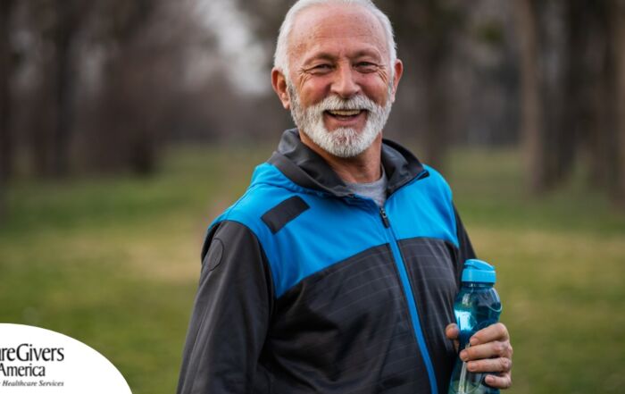 An older man smiles with a water bottle while exercising, representing the benefits of encouraging exercise when caring for seniors at home.