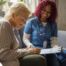 A healthcare professional helps an older patient fill out a form, representing what happens when the requirements for home health care eligibility are met.