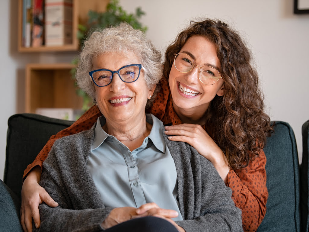 Smiling senior woman and female caregiver posing happily for a photograph, capturing a joyful moment that reflects the warmth of companion care.