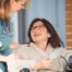 A care provider helps a patient in a wheelchair representing the benefits of medical care at home.