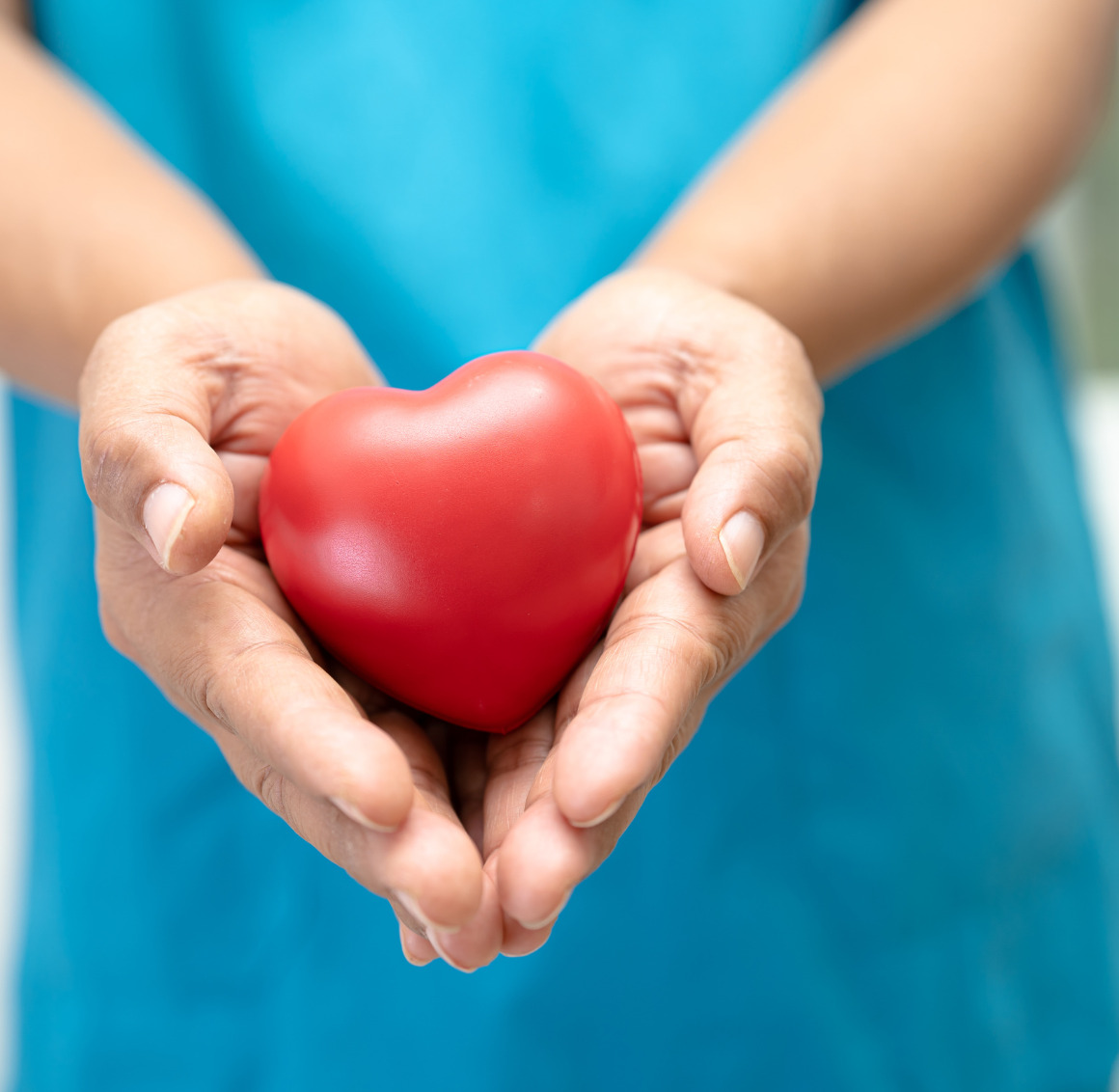 Close-up of a hand gently holding a heart-shaped object in the palm, symbolizing care, love, and compassion.