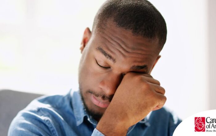 A man tiredly rubs his eyes, representing the exhaustion that can come with family caregiving.