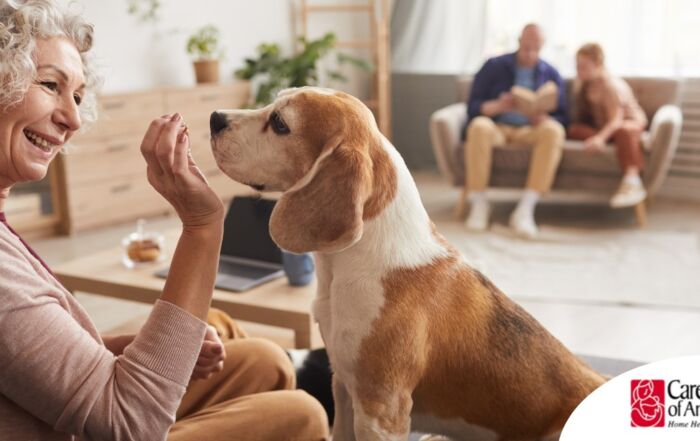 An older woman smiles while giving a dog a treat, representing the joy that dogs can bring.