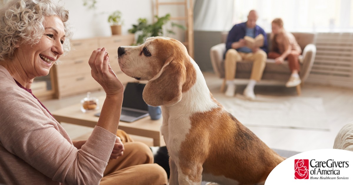 An older woman smiles while giving a dog a treat, representing the joy that dogs can bring.