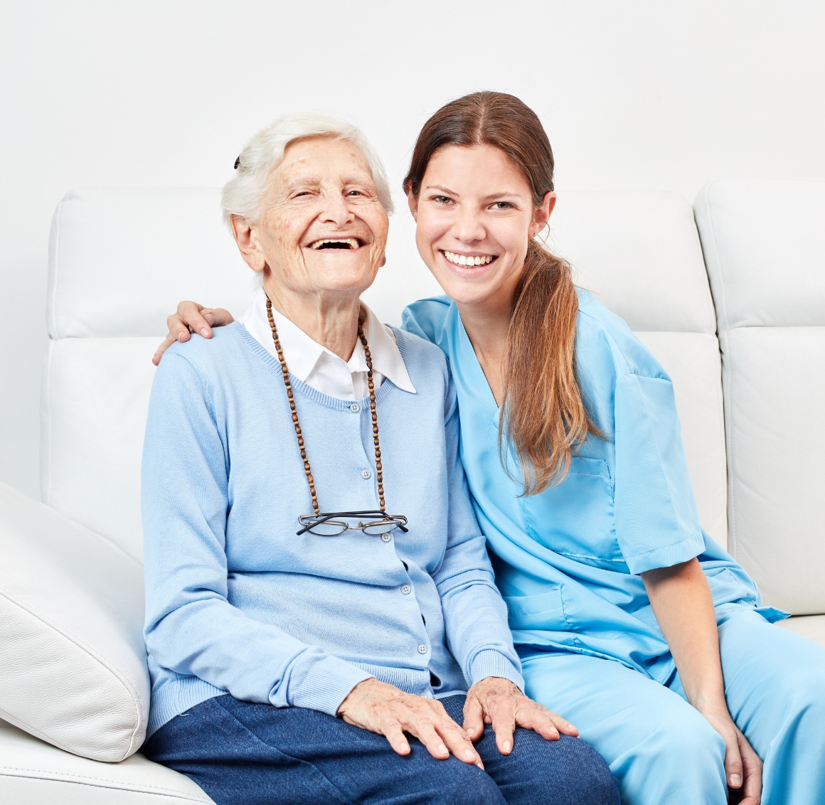A caregiver and an elderly woman share a joyful moment on the sofa, capturing the warmth and connection that define companion care in Fort Lauderdale.