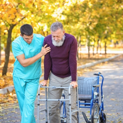 Companion Care in St. Andrews – Supportive Senior Assistance A caregiver in scrubs is assisting a senior man with a walker outdoors, showing encouragement, safety, and reliable companion care.