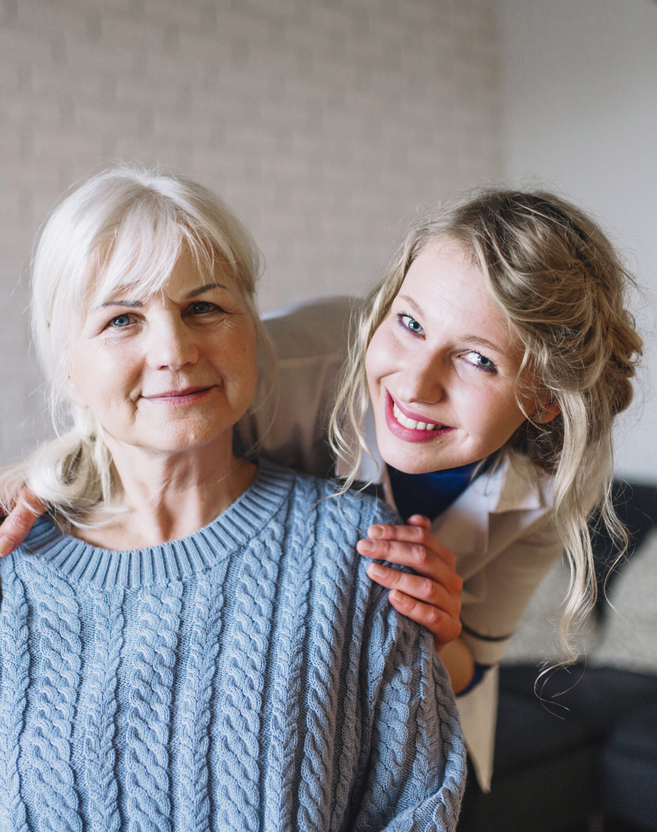 Compassionate Home Companionship Care A smiling caregiver stands beside an elderly woman, gently resting her hands on her shoulders, symbolizing warmth, trust, and companionship.