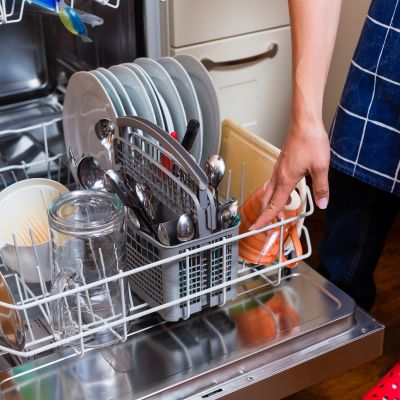Caregiver loading dishes into a dishwasher during light housekeeping services in Margate.