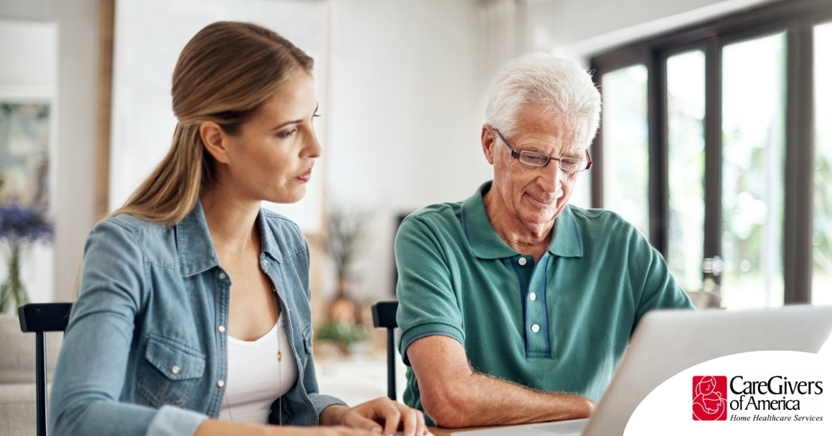 Adult daughter and senior father talking at a kitchen table while comparing home care vs assisted living